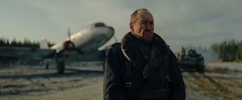 Movie still from “Sisu” (2022), directed by Jalmari Helander – An older man wearing a coat and a fur collar; Medium shot, Low angle
