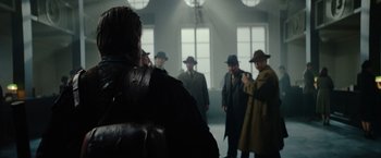 Movie still from “Sisu” (2022), directed by Jalmari Helander – A group of men standing around in a room; Medium shot, Over the shoulder angle