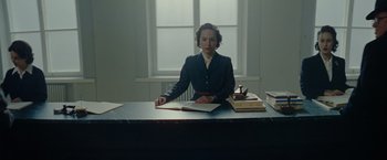 Movie still from “Sisu” (2022), directed by Jalmari Helander – A woman sitting at a table with a book; Medium shot, Low angle