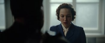 Movie still from “Sisu” (2022), directed by Jalmari Helander – A woman wearing a suit looking at her reflection in a mirror; Close Up shot, Over the shoulder angle
