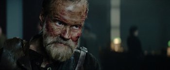 Movie still from “Sisu” (2022), directed by Jalmari Helander – An old man with a beard and face paint; Close Up shot, Over the shoulder angle
