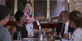 Movie still from “Sitting in Bars with Cake” (2023), directed by Trish Sie – Two people sitting at a dinner table with a waitress; Medium shot, Over the shoulder angle