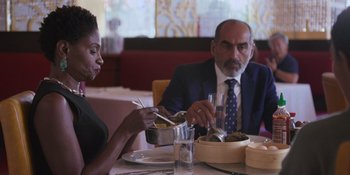 Movie still from “Sitting in Bars with Cake” (2023), directed by Trish Sie – A man and a woman sitting at a restaurant table; Close Up shot, Over the shoulder angle