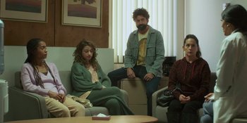 Movie still from “Sitting in Bars with Cake” (2023), directed by Trish Sie – A group of people sitting on a couch in a living room; Wide shot, High angle