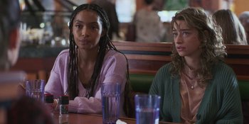 Movie still from “Sitting in Bars with Cake” (2023), directed by Trish Sie – Two women sitting at a table in a restaurant; Medium shot, Over the shoulder angle
