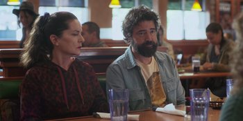 Movie still from “Sitting in Bars with Cake” (2023), directed by Trish Sie – A man and a woman sitting at a table in a restaurant; Medium shot, Over the shoulder angle
