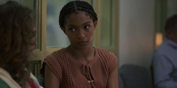 Movie still from “Sitting in Bars with Cake” (2023), directed by Trish Sie – A young woman with a brown sweater looking at the camera; Close Up shot, Over the shoulder angle