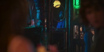 Movie still from “Sitting in Bars with Cake” (2023), directed by Trish Sie – A man sitting in a chair in a room; Medium shot, Low angle