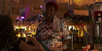 Movie still from “Sitting in Bars with Cake” (2023), directed by Trish Sie – A man in a hawaiian shirt is holding a cake; Medium shot, Over the shoulder angle