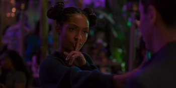 Movie still from “Sitting in Bars with Cake” (2023), directed by Trish Sie – A woman with two buns is posing for a picture; Close Up shot, Over the shoulder angle