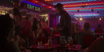 Movie still from “Sitting in Bars with Cake” (2023), directed by Trish Sie – A man and a woman are sitting at a table in a restaurant; Medium shot, Over the shoulder angle