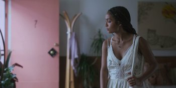 Movie still from “Sitting in Bars with Cake” (2023), directed by Trish Sie – A woman in a white dress standing in front of a mirror; Medium shot, Over the shoulder angle