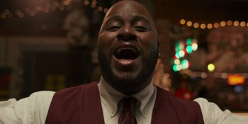 Movie still from “Sitting in Bars with Cake” (2023), directed by Trish Sie – A person wearing a suit and tie; Close Up shot, Low angle