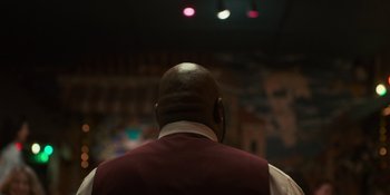 Movie still from “Sitting in Bars with Cake” (2023), directed by Trish Sie – A man in a red vest and white shirt is looking at a wall; Close Up shot, Low angle