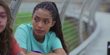 Movie still from “Sitting in Bars with Cake” (2023), directed by Trish Sie – A young woman sitting on top of a wooden bench; Close Up shot, Over the shoulder angle