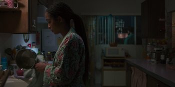 Movie still from “Sitting in Bars with Cake” (2023), directed by Trish Sie – A woman standing in a kitchen with her hands on her hips; Medium shot, Over the shoulder angle