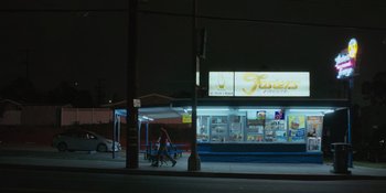 Movie still from “Sitting in Bars with Cake” (2023), directed by Trish Sie – Two people walking down the sidewalk at night; Extreme Wide shot, High angle