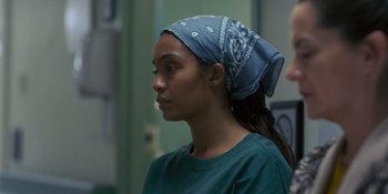 Movie still from “Sitting in Bars with Cake” (2023), directed by Trish Sie – A woman with a bandanna around her head; Close Up shot, Over the shoulder angle