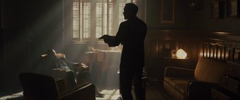 Movie still from “Skyfall” (2012), directed by Sam Mendes – A man standing in front of a window holding a remote control; Wide shot, Low angle