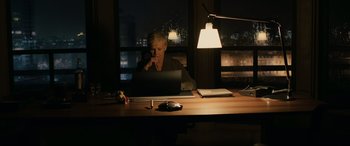 Movie still from “Skyfall” (2012), directed by Sam Mendes – A woman sitting in front of a laptop computer at a desk; Medium shot, High angle