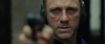 Movie still from “Skyfall” (2012), directed by Sam Mendes – A person wearing headphones and holding a gun; Close Up shot, Low angle
