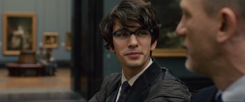 Movie still from “Skyfall” (2012), directed by Sam Mendes – A young man wearing glasses and a jacket; Close Up shot, Over the shoulder angle