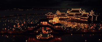 Movie still from “Skyfall” (2012), directed by Sam Mendes – A night view of a lake with a bridge lit up with lights; Extreme Wide shot, High angle