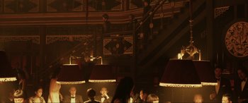 Movie still from “Skyfall” (2012), directed by Sam Mendes – A group of people sitting at a table in front of a staircase; Wide shot, High angle