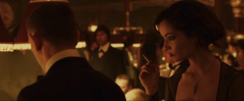 Movie still from “Skyfall” (2012), directed by Sam Mendes – A woman smoking a cigarette in front of other people; Close Up shot, Over the shoulder angle