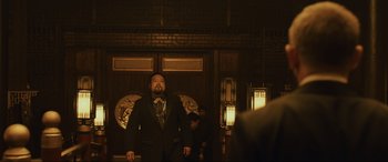 Movie still from “Skyfall” (2012), directed by Sam Mendes – A man in a suit standing in front of a building; Medium shot, Low angle