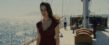 Movie still from “Skyfall” (2012), directed by Sam Mendes – A woman in a red dress standing on a boat in the ocean; Medium shot, Low angle