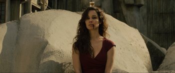 Movie still from “Skyfall” (2012), directed by Sam Mendes – A woman in a red dress is sitting in front of a pile of rocks; Close Up shot, Low angle