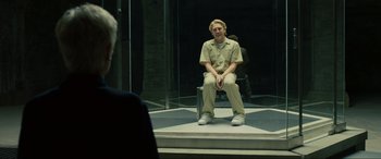 Movie still from “Skyfall” (2012), directed by Sam Mendes – A man sitting on a chair in front of a glass wall; Medium shot, Over the shoulder angle
