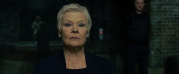Movie still from “Skyfall” (2012), directed by Sam Mendes – An older woman with short blonde hair wearing a black top; Close Up shot, Low angle