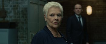 Movie still from “Skyfall” (2012), directed by Sam Mendes – An older woman with white blonde hair wearing a black jacket; Close Up shot, Low angle