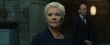 Movie still from “Skyfall” (2012), directed by Sam Mendes – An older woman with short blonde hair wearing a black top; Close Up shot, Low angle