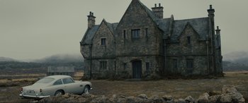 Movie still from “Skyfall” (2012), directed by Sam Mendes – An old stone house with a car parked in front of it; Extreme Wide shot, Low angle