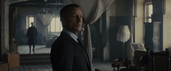 Movie still from “Skyfall” (2012), directed by Sam Mendes – A man wearing a suit and tie standing in a room; Medium shot, Low angle