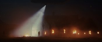 Movie still from “Skyfall” (2012), directed by Sam Mendes – A man standing in front of a building on fire at night; Extreme Wide shot, Low angle