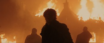 Movie still from “Skyfall” (2012), directed by Sam Mendes – A man standing in front of a burning building; Medium shot, Low angle