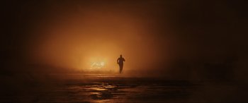 Movie still from “Skyfall” (2012), directed by Sam Mendes – A man running on a beach at night with a fire in the background; Extreme Wide shot, Low angle