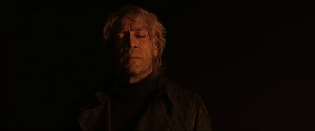Movie still from “Skyfall” (2012), directed by Sam Mendes – A man with long blonde hair and wearing a black jacket; Close Up shot, Low angle