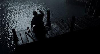 Movie still from “Sleepy Hollow” (1999), directed by Tim Burton – A person sitting on a dock in the dark; Wide shot, Low angle