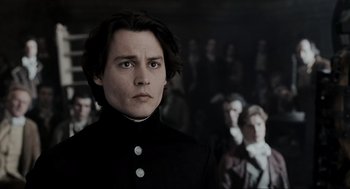 Movie still from “Sleepy Hollow” (1999), directed by Tim Burton – A man in a black suit standing in front of a group of people; Close Up shot, Over the shoulder angle