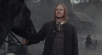 Movie still from “Sleepy Hollow” (1999), directed by Tim Burton – A man standing next to a horse in a field; Medium shot, Low angle