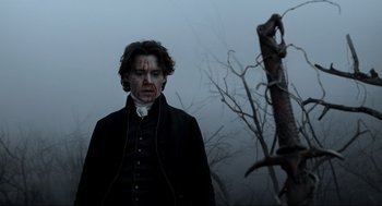 Movie still from “Sleepy Hollow” (1999), directed by Tim Burton – A man in a black jacket and a tree in the fog; Medium shot, Low angle