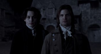 Movie still from “Sleepy Hollow” (1999), directed by Tim Burton – Two men standing next to each other in front of a building; Medium shot, Low angle