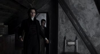 Movie still from “Sleepy Hollow” (1999), directed by Tim Burton – A man in a suit and tie standing next to another man in a suit and tie; Medium shot, Low angle