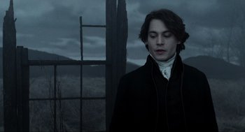 Movie still from “Sleepy Hollow” (1999), directed by Tim Burton – A man in a black jacket standing in front of a window; Medium shot, Low angle