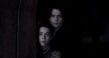 Movie still from “Sleepy Hollow” (1999), directed by Tim Burton – Two young men standing next to each other in front of a tree; Medium shot, Low angle